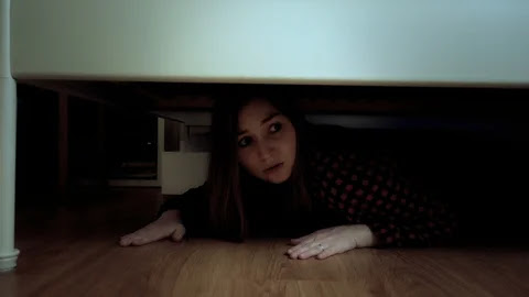 A woman goes beneath the bed to spy on her spouse.