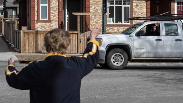 Every day, a kind 85-year-old stands on a street corner, waving and blowing kisses to cheer up her community.